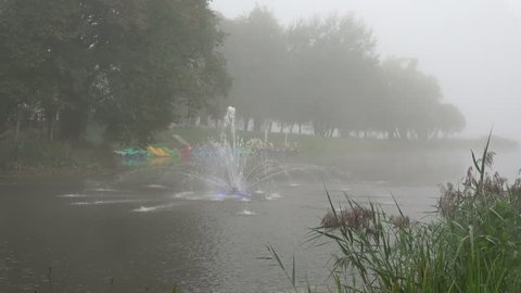 Fountain on river water and dark morning mist fog