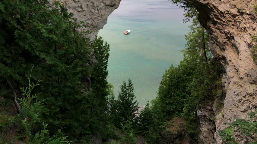 Beautiful view of boat from under Arch Rock in Mackinac Island, Michigan, USA. Turquoise waters enhance the dramatic look (not color graded)