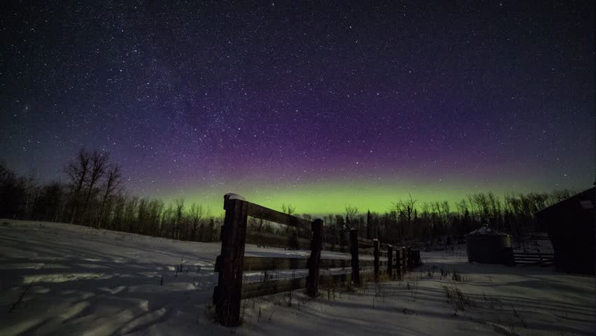 Winter time lapse of the northern lights and stars over a wooden fence and grain bin on an abandoned farm in Alberta, Canada