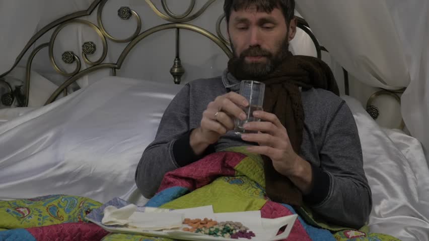 Sad sick man with a warm scarf around his neck, coughing and drinks a pills. runny nose during a cold or influenza. slow motion Royalty-Free Stock Footage #1016778904
