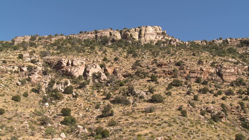 Static shot of the foothills of the Catalina Mountains with rugged peaks rising in the distance on a sunny day with blue skies, near Tuscon, Arizona