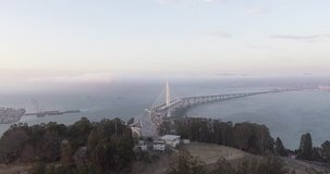 Aerial footage from Treasure Island in San Francisco, flying over the water towards the San Francisco-Oakland Bay Bridge and the Oakland skyline.