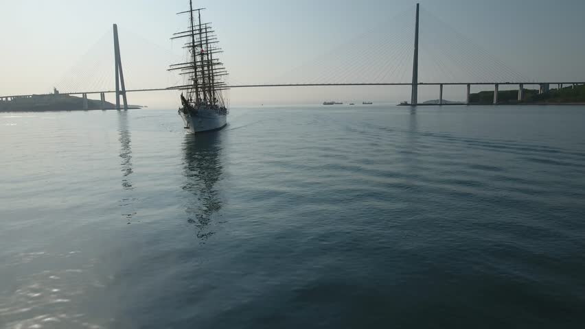 Aerial approach silhouette Beautiful old ship vessel sailboat frigate Navy fleet. Russian cable bridge. Sea Bosporus shining water Sunrise. Traveling tourism Luxe cruise. Landmark. Vladivostok Russia 