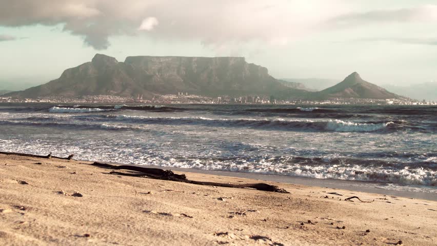 Full view of Table Mountain in Cape Town, South Africa with sand and sea in the foreground.