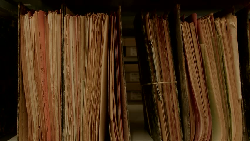Camera movement along a file shelf. The paper of the files is old. In the background of the archive are even more shelves.The image can be used for the integration of archive texts in films and report Royalty-Free Stock Footage #1016795257
