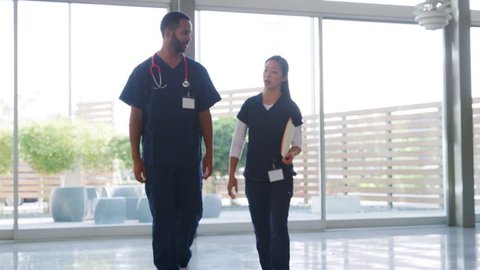 Male doctor and female nurse walk to the camera in hospital