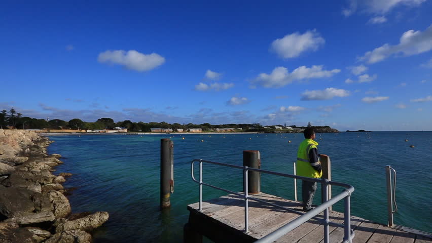 Beautiful landscape footage of male standing enjoying watching looking at sunrise at the pier Thomson Bay isolated rottnest Island blue sky for travellers holiday destination in Perth WA Australia    