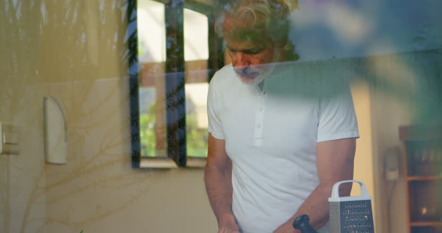 Front view of Caucasian senior man chopping vegetable in kitchen 