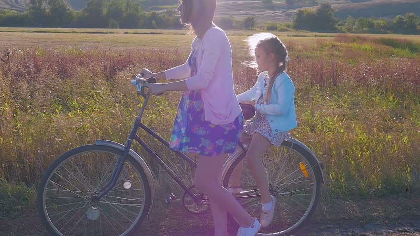 Mother with daughter on bicycles in a meadow. Family on bicycles in nature. The concept of the family.