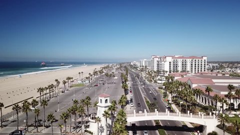 Pacific Coast Highway Past Huntington Beach Drone Aerial of Hotels and Pier
 To the left can be seen beach condominiums and apartments. To the right the beach park, beach and ocean.
