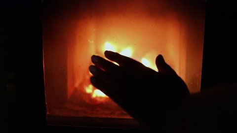 Silhouette of woman hand against burning fireplace