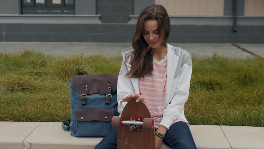Beautiful young girl woman with his longboard on the road in the city in sunny weather skateboard skater smiling backpack student