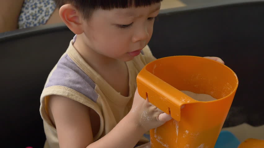 slow motion scene, cute child playing sand in playground