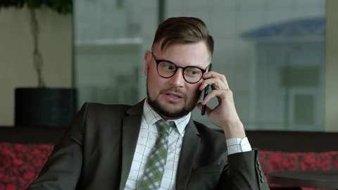 Successful businessman in eyeglasses talking on the mobile phone in office. 4k uhd