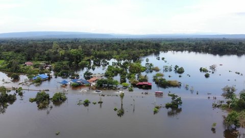 Aerial drone cinematic footage traffic driving through a flooded road in Laos, South East Asia. During monsoon season, many towns and roads flood from the growing Mekong River. 
