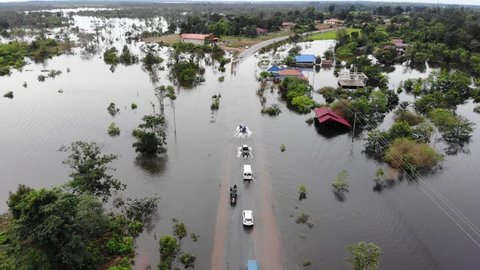 Aerial drone cinematic footage traffic driving through a flooded road in Laos, South East Asia. During monsoon season, many towns and roads flood from the growing Mekong River. 