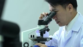 Scientist male is looking through microscope working in modern laboratory or medical center. Concept of science, testing development and lab industry.
