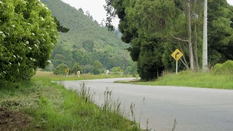 A wide shot of a empty road in the countryside with the mountains as a background