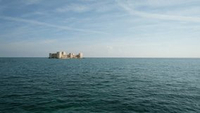 Distant wide angle still view from middle of ocean to Kizkalesi island castle on the Mediterranean Sea in Turkey