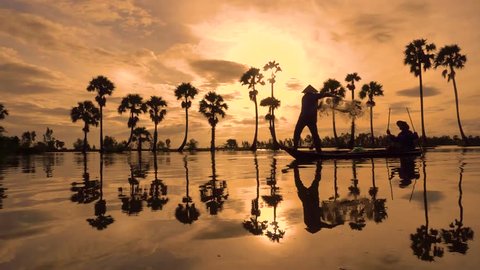 Silhouette of fishermen or fisherman throw fishing nets to catch fish at the pond in the sky morning. Slow motion footage of silhouette fisherman or fisher throwing a fishing net in yellow sky sunrise