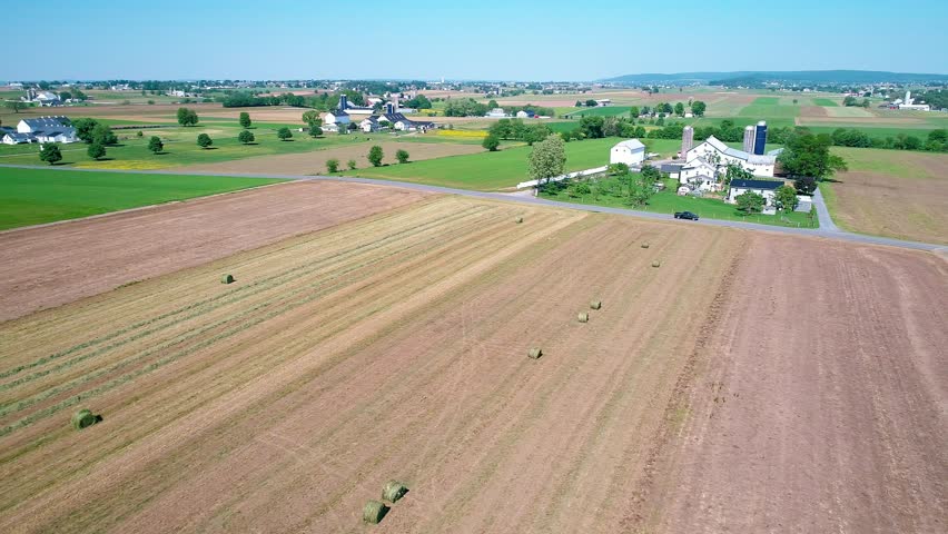 Amish Farm Worker Harvesting the Fields with old and New Equipment