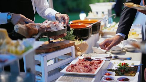 Catering table with food and hands of people in Restaurant outdoor. People group catering buffet food. Food service worker