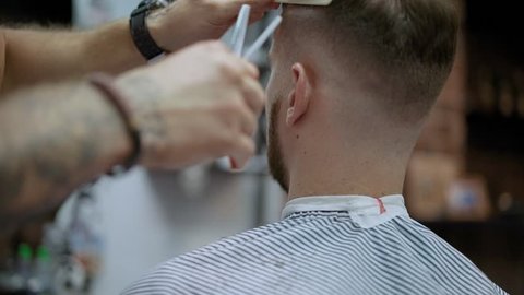 Barber trimming man hair in haircutter shop. Hair is a man. The man in the barber shop. Barbershop with master