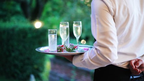 Waiter and champagne glasses on a tray in Luxury Restaurant. Catering service. 4k