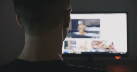 Back view of man communicates through porn chat virtual sex at night