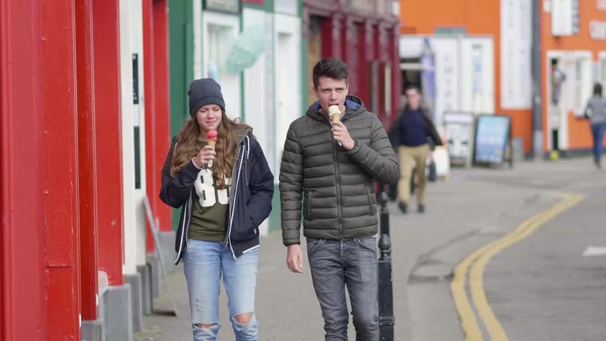 Young couple walks down the streets and eats ice cream