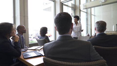 Businesswoman writing on glass while giving presentation in board room