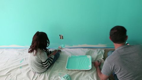 Handheld shot of father and daughter painting wall at home