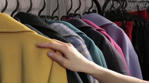 Female hands selecting colorful clothes on hangers
