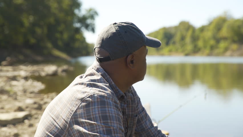 Handheld close-up shot of thoughtful man sitting in boat by lake at forest