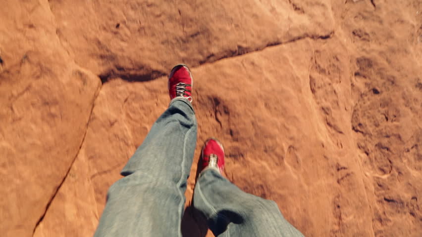 Handheld shot of hiker walking on rocks at Arches National Park