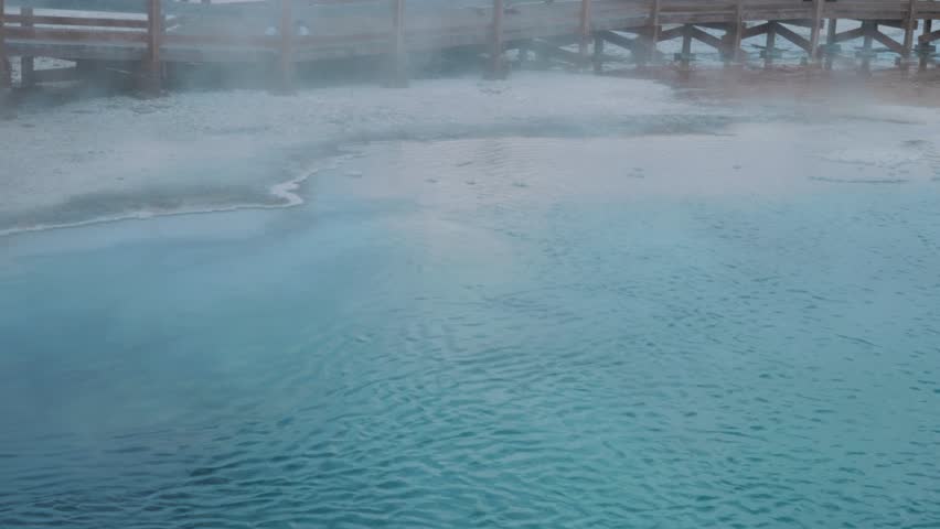 Steam rises from a blue natural hotspring in Yellowstone National Park