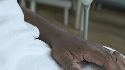 Handheld shot of female doctor holding patient's hand at hospital