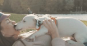 Portrait of beautiful young woman playing with dog jack russell terrier on the lake shore. A girl kissing a cute puppy. 4K video shooting