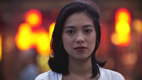 Close up of one lovely pretty young again girl smile at camera in the street with with blurred asian red lantern street at background 4k slow motion