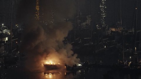 During the night, firefighters try to put out two luxury yachts that are catching fire at the marina berth
