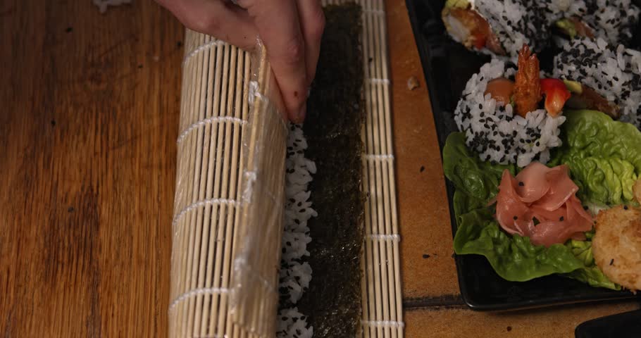 Wrapping or rolling sushi on wooden table. Homemade japanesse food.