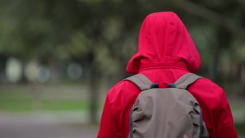 Rear view of man in red hood turn face and go away in park