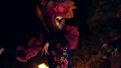 The face of the girl at the masquerade in a Venetian suit hides a mysterious mask. Dance with fire in the night. Concept idea for dance