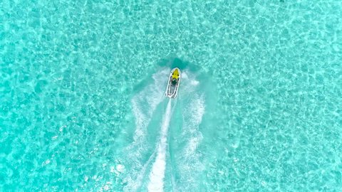 Aerial - Top view of  jet ski racing on a crystal clear water. Adult male enjoying summer vacation in Bora Bora on a jet ski 