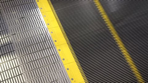 Escalator in metro, shopping mall. Moving up staircase escalator to Moving electric escalator.Close up floor platform electric escalator. yellow bands metal line steel. yellow gray steel line