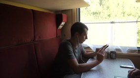 silhouette of man on a train railway car listening to music on headphones writing a message in a messenger social media smartphone. slow motion video travel by train 