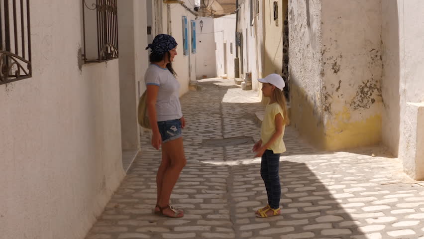 Funny mom and daughter dancing like little duck while walk along city street