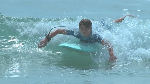 Young people in ocean surf enjoying the summer waves in slow motion