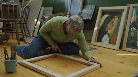 Panning shot of woman carving wooden frame for paintings / Spring City, Utah, United States