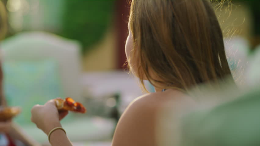 Close up of happy girls sitting poolside laughing and eating pizza / Cedar Hills, Utah, United States